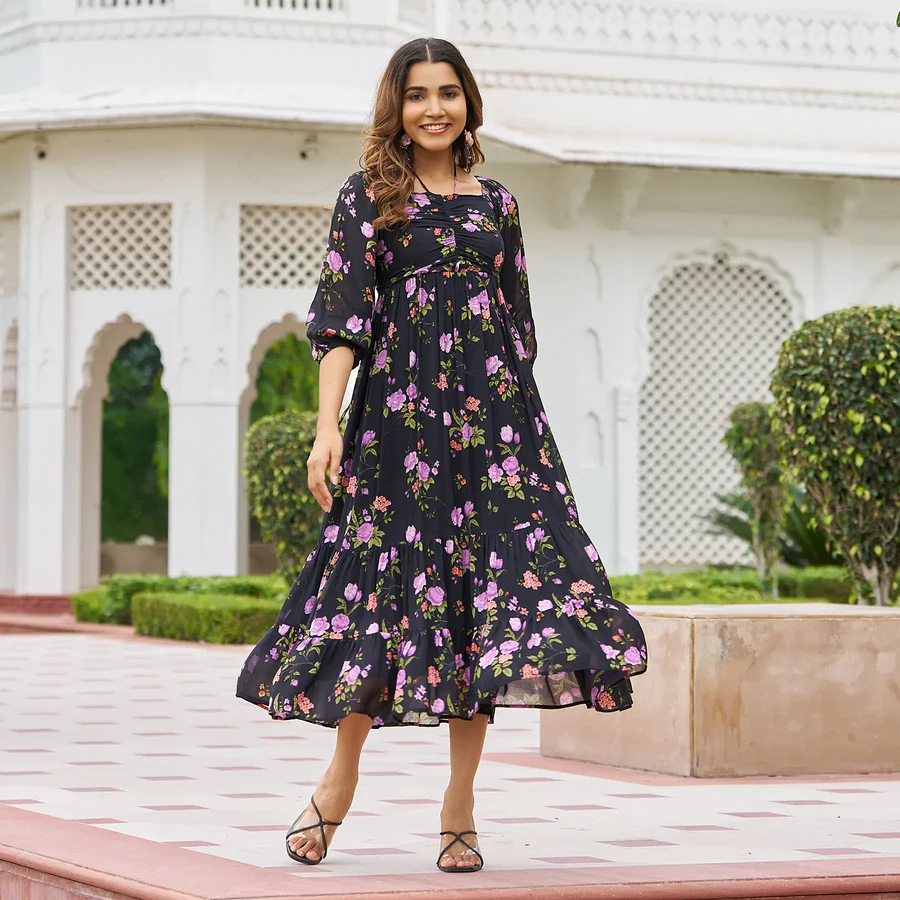 Woman in black floral dress walking and smiling outdoors.