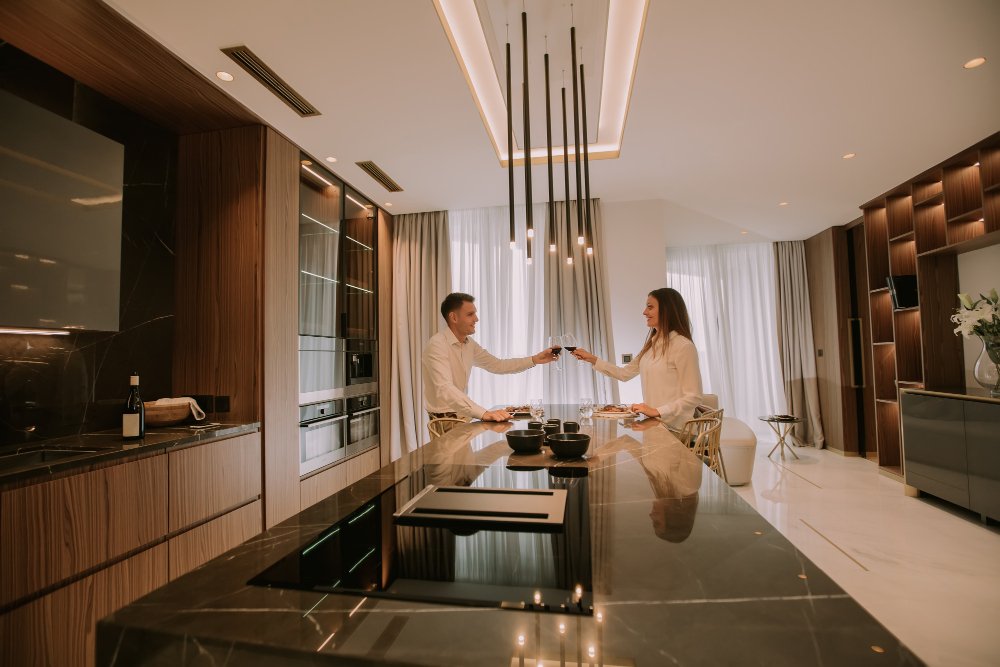 Man and woman clinking wine glasses while having dinner in their suite