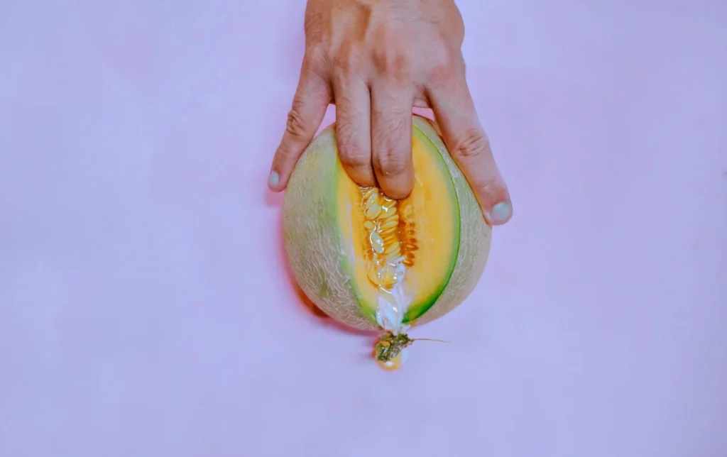 A symbolic visual of sexual exploration featuring a hand and melon, used in a Beginner’s Guide to Exploring Kinks Safely.