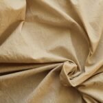 Beige linen fabric texture with natural folds and creases, close-up background for home textiles and bedding