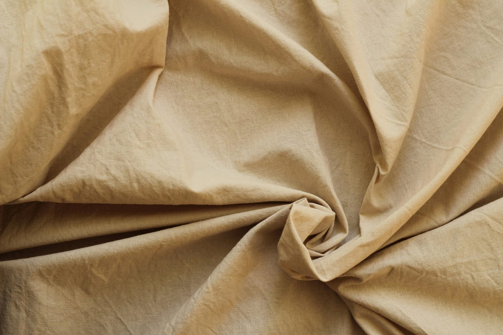 Beige linen fabric texture with natural folds and creases, close-up background for home textiles and bedding